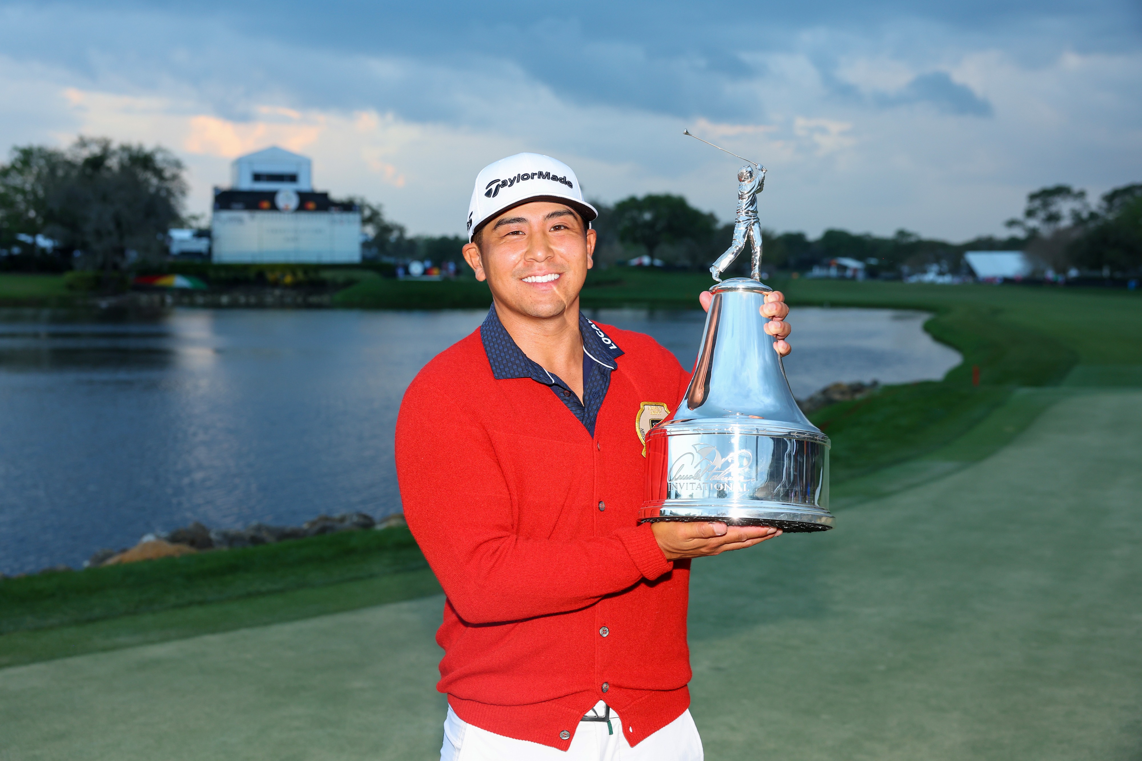 Kurt Kitayama hoists his first career PGA TOUR trophy while donning the signature Palmer Cardigan